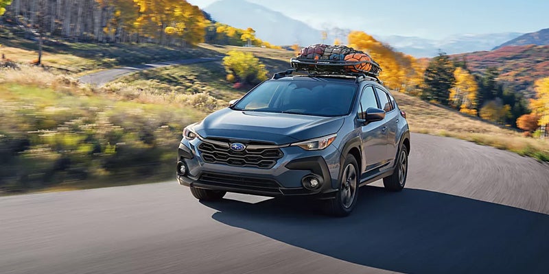 Subaru crosstrek driving on a scenic mountain road with roof cargo